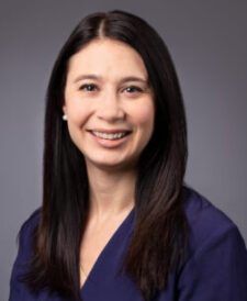 woman with long straight dark hair past shoulders wearing deep purple blue shirt smiling