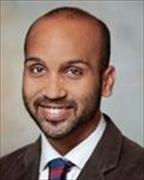 Headshot of man with facial hair wearing white shirt dark tie and suitjacket smiling