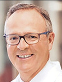 headshot of man with gray/brown hair and eyeglasses smiling broadly