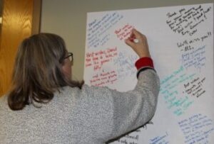 Woman writing on very large retirement card on wall