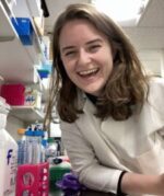 Erin Hennessey in lab leaning on table with broad smile