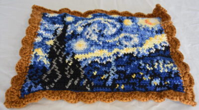 Crocheted Starry Night in shades of blue, yellow, white, black with a gold scalloped border
