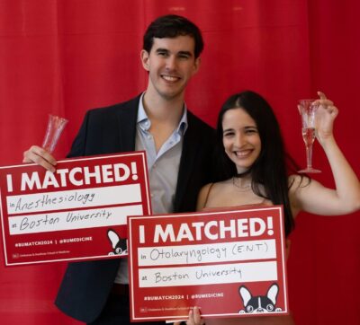 Man and woman holding match signs in front of red curtain