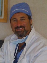 Fredric Meyer in whitecoat, light blue scrubs, cap and mask