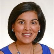 Head and shoulders of Priya Garg, chin length straight dark brown/black hair, smiling broadly