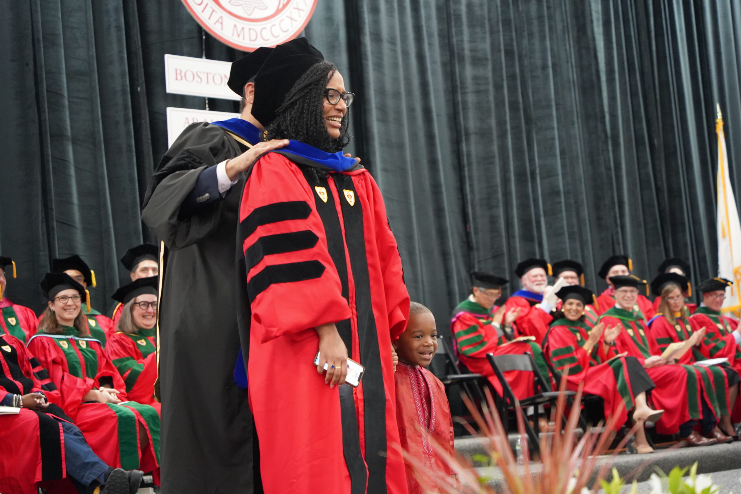 PhD student speaker Josiane Fofana standing with her son getting hooded