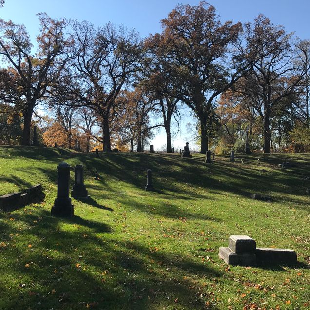 Cemetary in spring, green grass, blue sky, open space, headstones