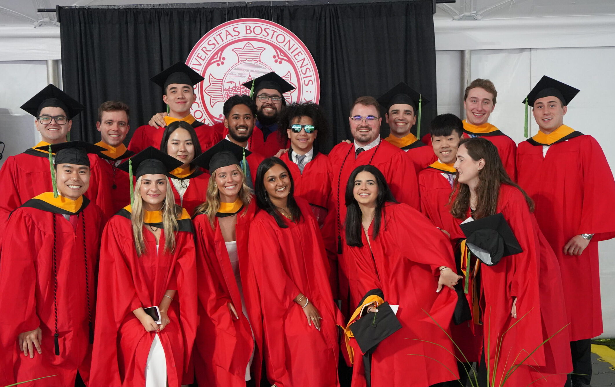 Group shot of students after conovocation at reception in front of BU seal