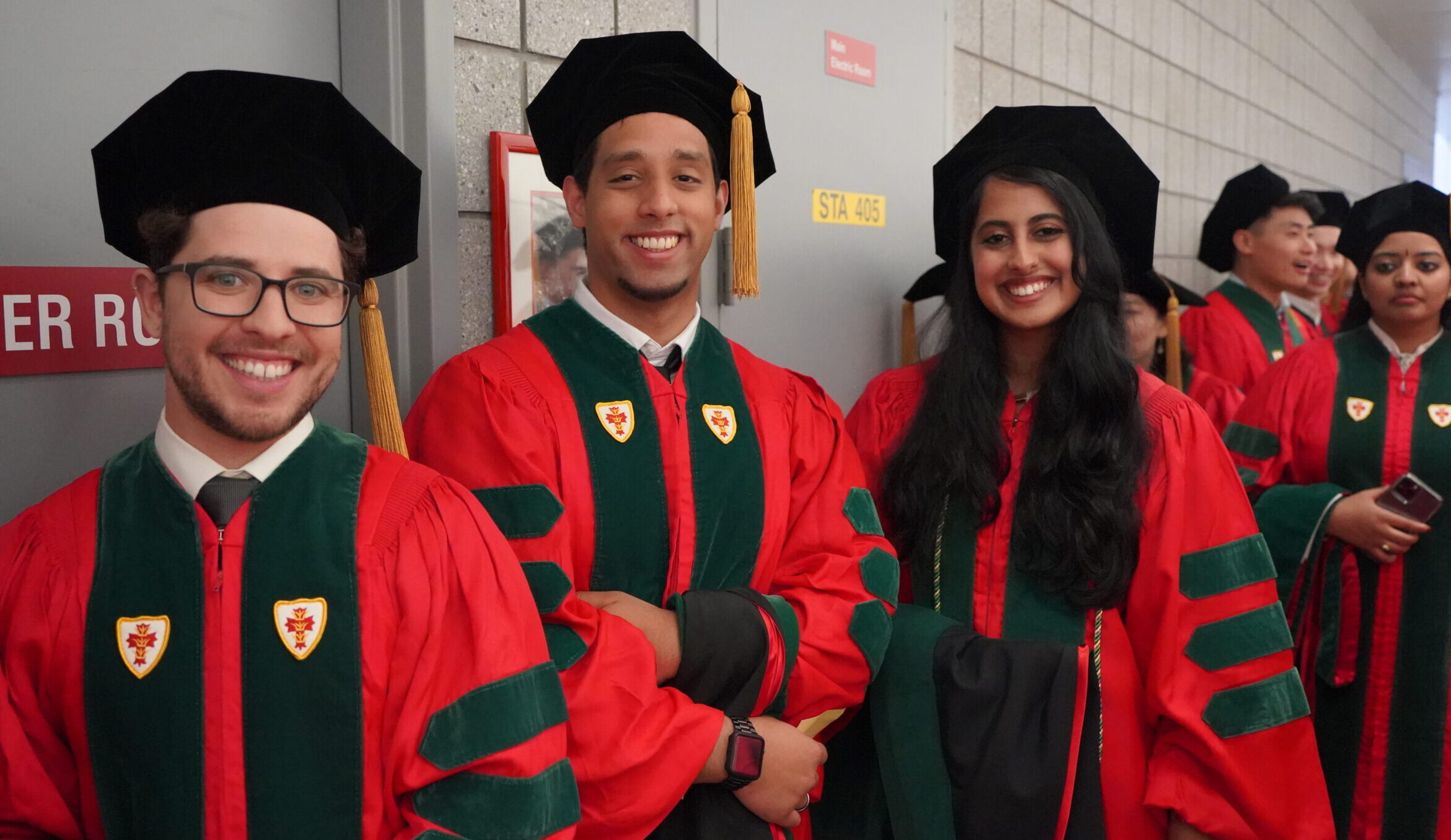 Three students in regalia lining up with their peers