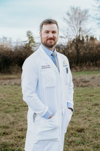 David Veltre standing, wearing whitecoat outside in field