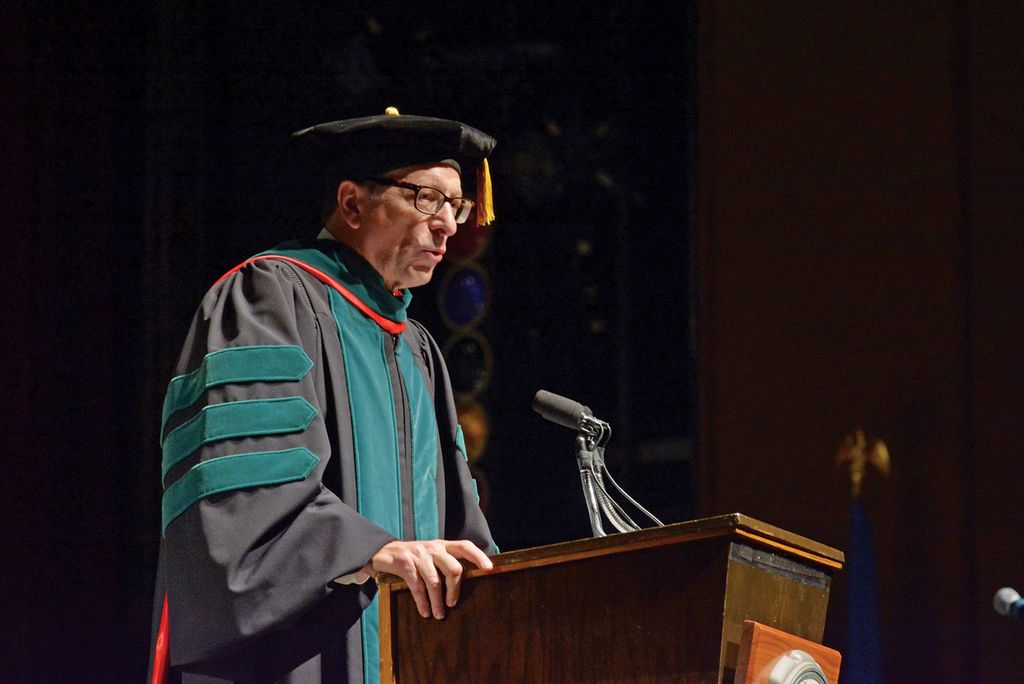 Joshua Wynne in regalia at podium