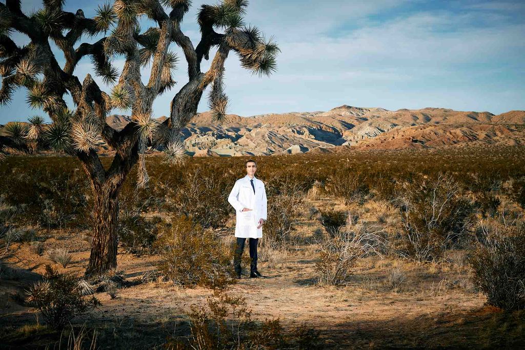 Vardan Papoian in a whitecoat standing outside with a desert behind