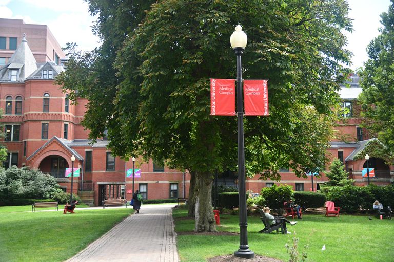A view of the BU Medical campus with students walking as other study in the grass.