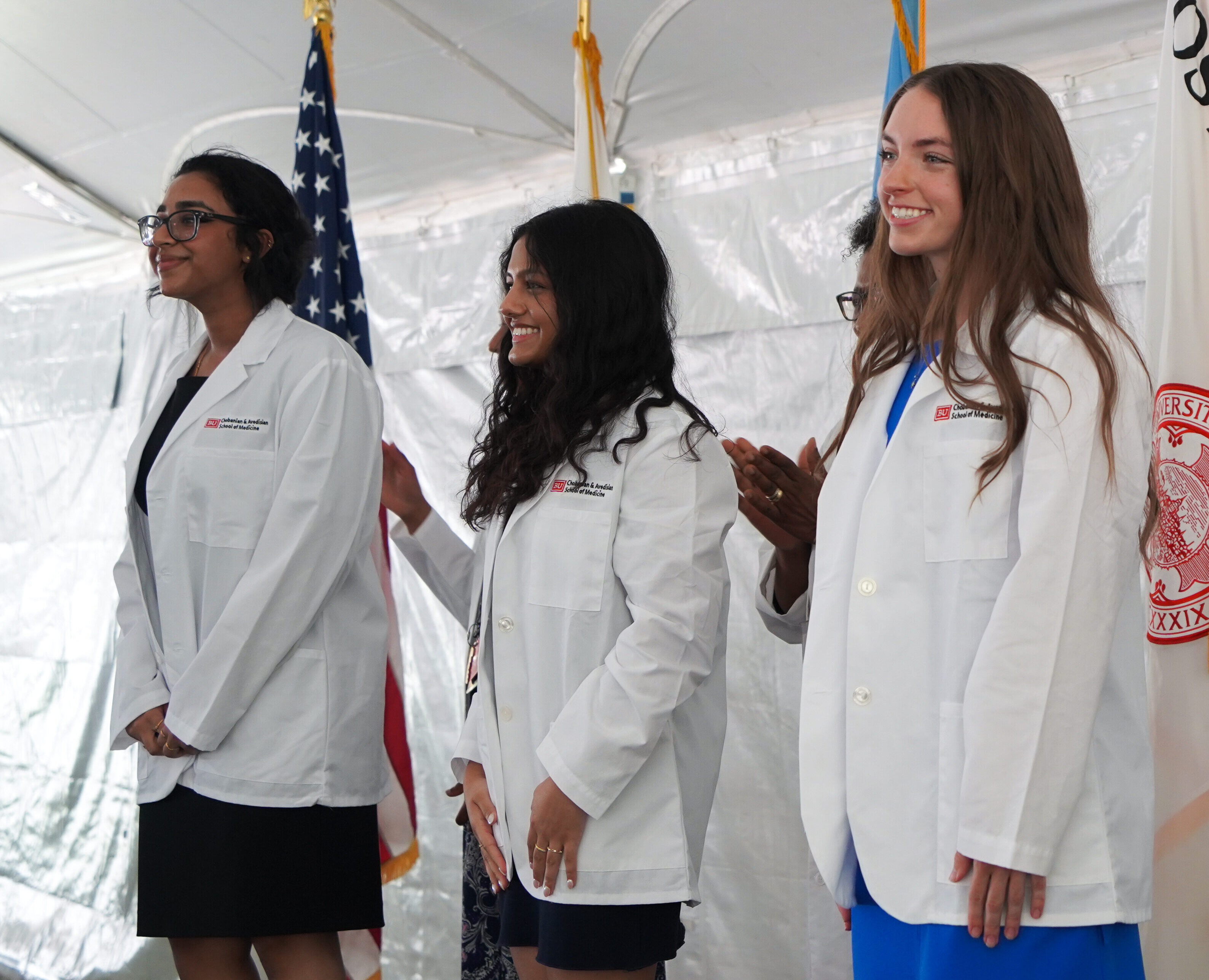 Three students wearing whitecoats on podium