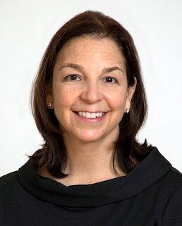 Head and shoulder shot of Heather Miselis wearing dark top, smiling broadly