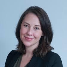 Head and shoulders of Abigail Batchelder shoulder length brown straight hair parted on side, dark suit jacket