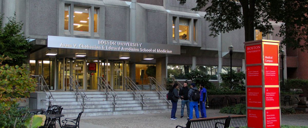 Entrance to Boston University School of Medicine with stairs, glass doors, and people near the entrance.