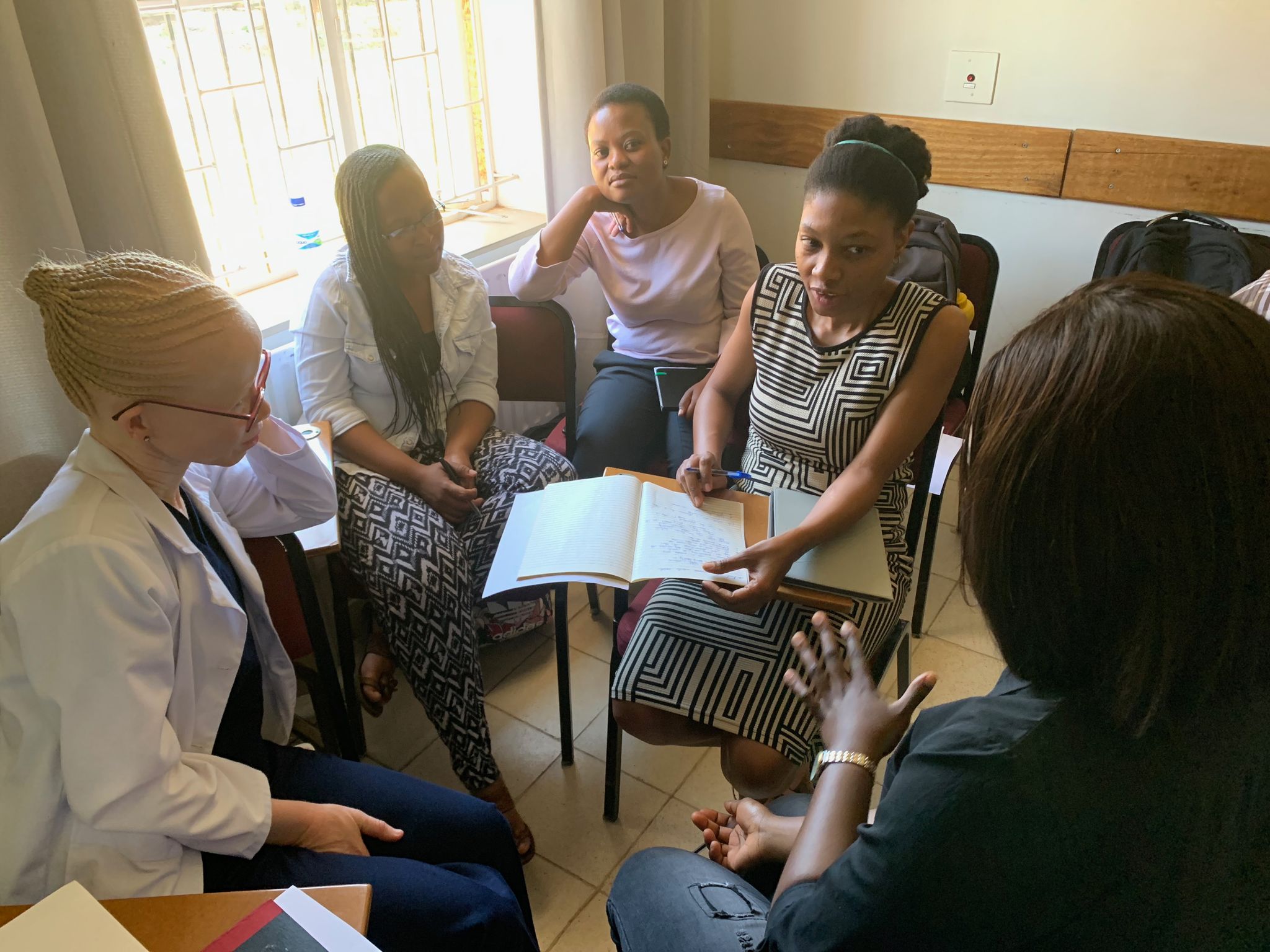 Six medical residents and interns meeting all sitting in chairs in a circle