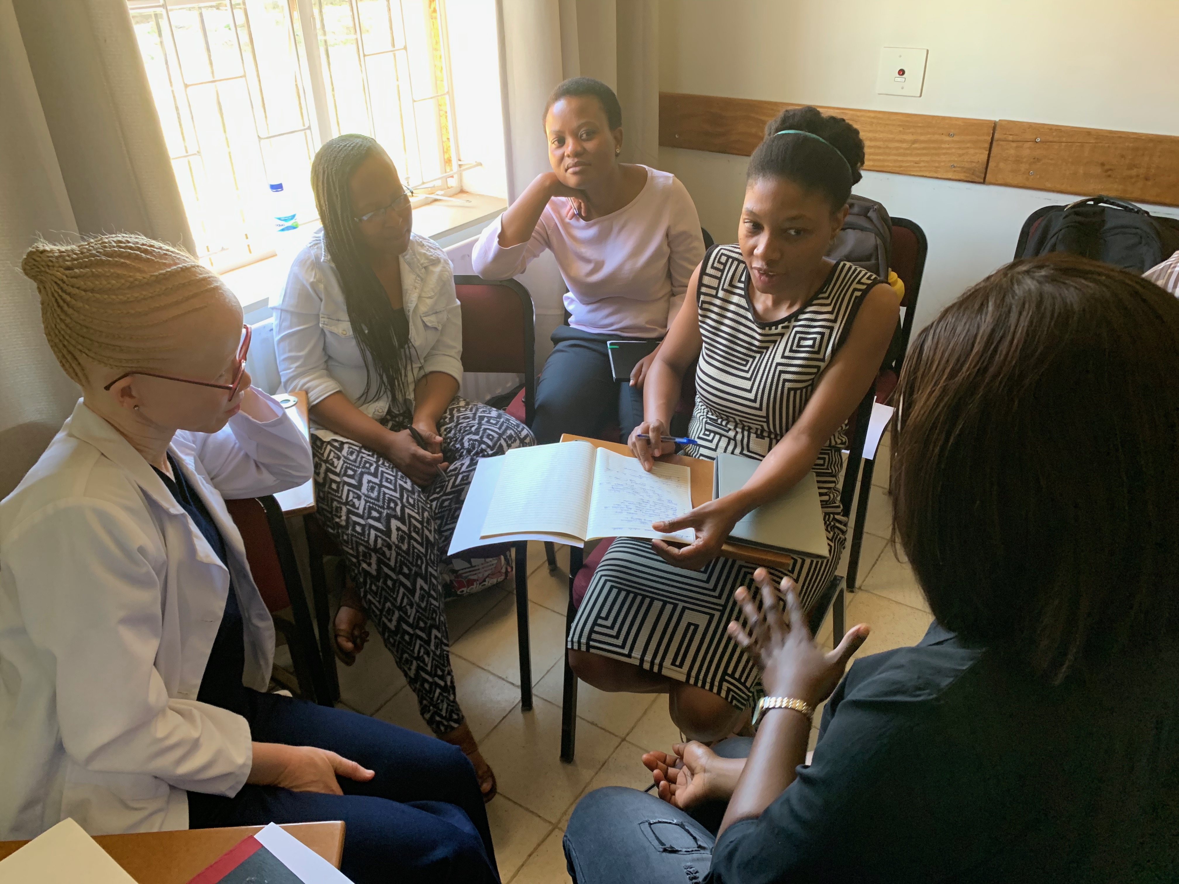 Six medical residents and interns meeting all sitting in chairs in a circle