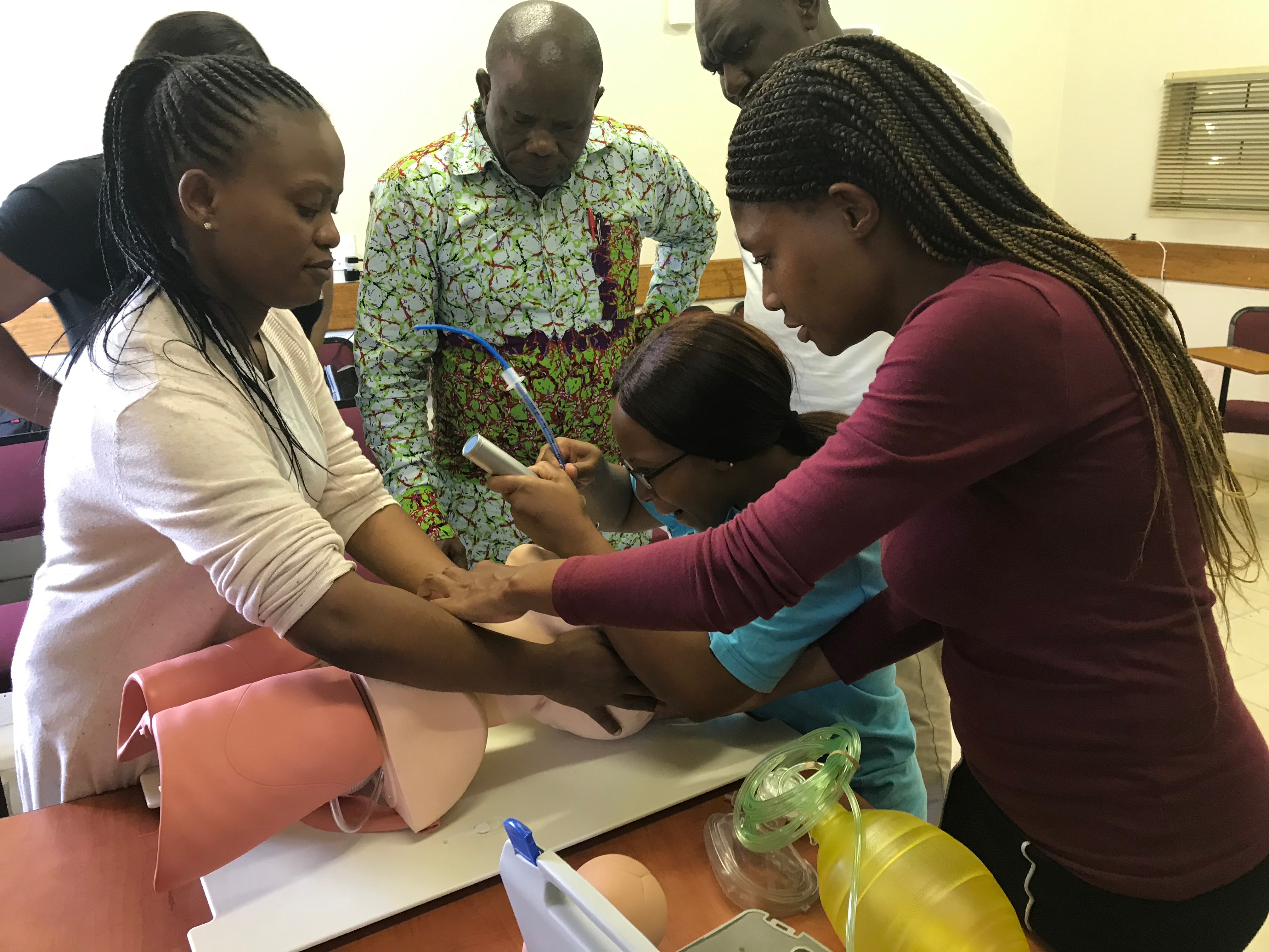 Group of six students gathered around a maniquin learning to perform a tracheotomy