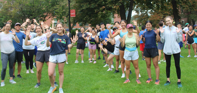 Students in athletic clothing gathered in an outdoor grassy area.