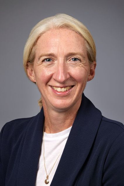 head and shoulders shot of Dr. Young wearing dark jacket, white shirt, blond hair pulled back into ponytail behind her head