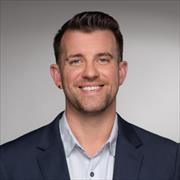Head and shoulders image of Carl Streed wearing dark suit jacket and light colored open collar buttondown shirt