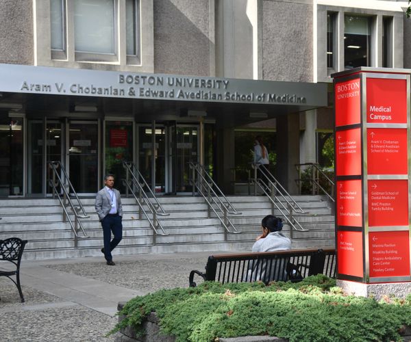 Entrance of Boston University's Chobanian & Avedisian School of Medicine with a red 'Medical Campus' sign, stairs, and people nearby.