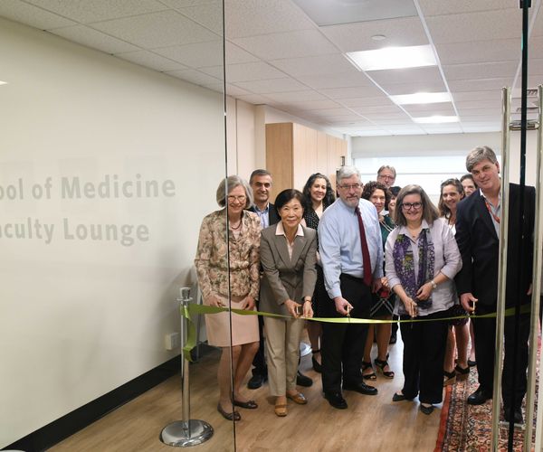 A group of faculty members cutting a ribbon during the opening ceremony of the School of Medicine Faculty Lounge