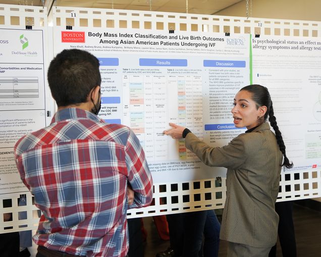 Nora Khalil explaining a research poster on BMI classification and live birth outcomes among Asian American IVF patients to an attendee