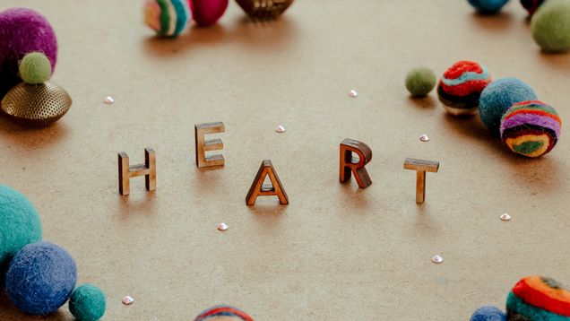 Heart spelled out in small capital letters with felt balls whimsically around it