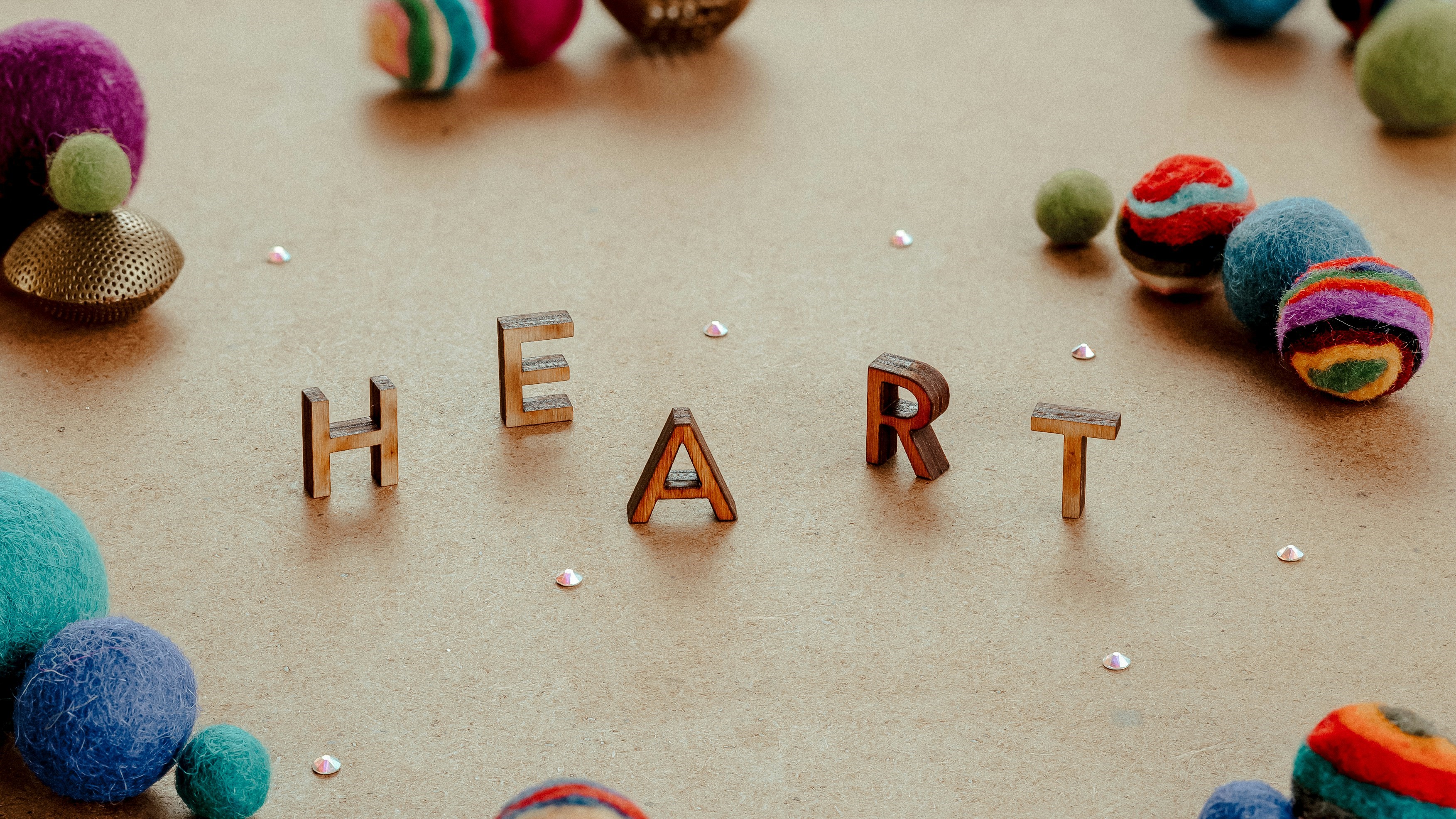 Heart spelled out in small capital letters with felt balls whimsically around it