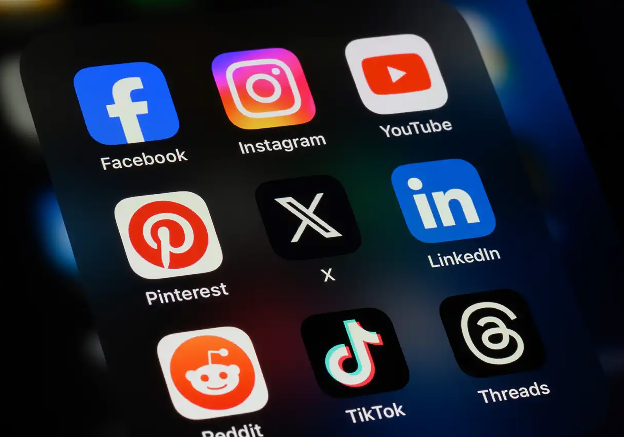 A close-up of a phone shows a grid listing of popular social media apps on screen.