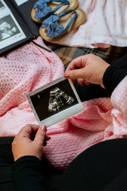 Woman examining ultrasound image pink baby blanket in her lap