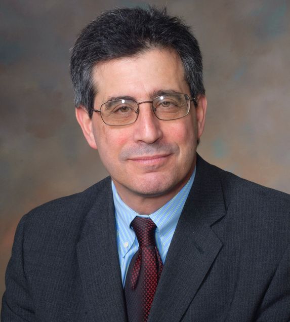 head and shoulders image of Howard Bauchner in dark gray suit, blue shirt, burgandy tie, gray hari, wearing eyeglasses