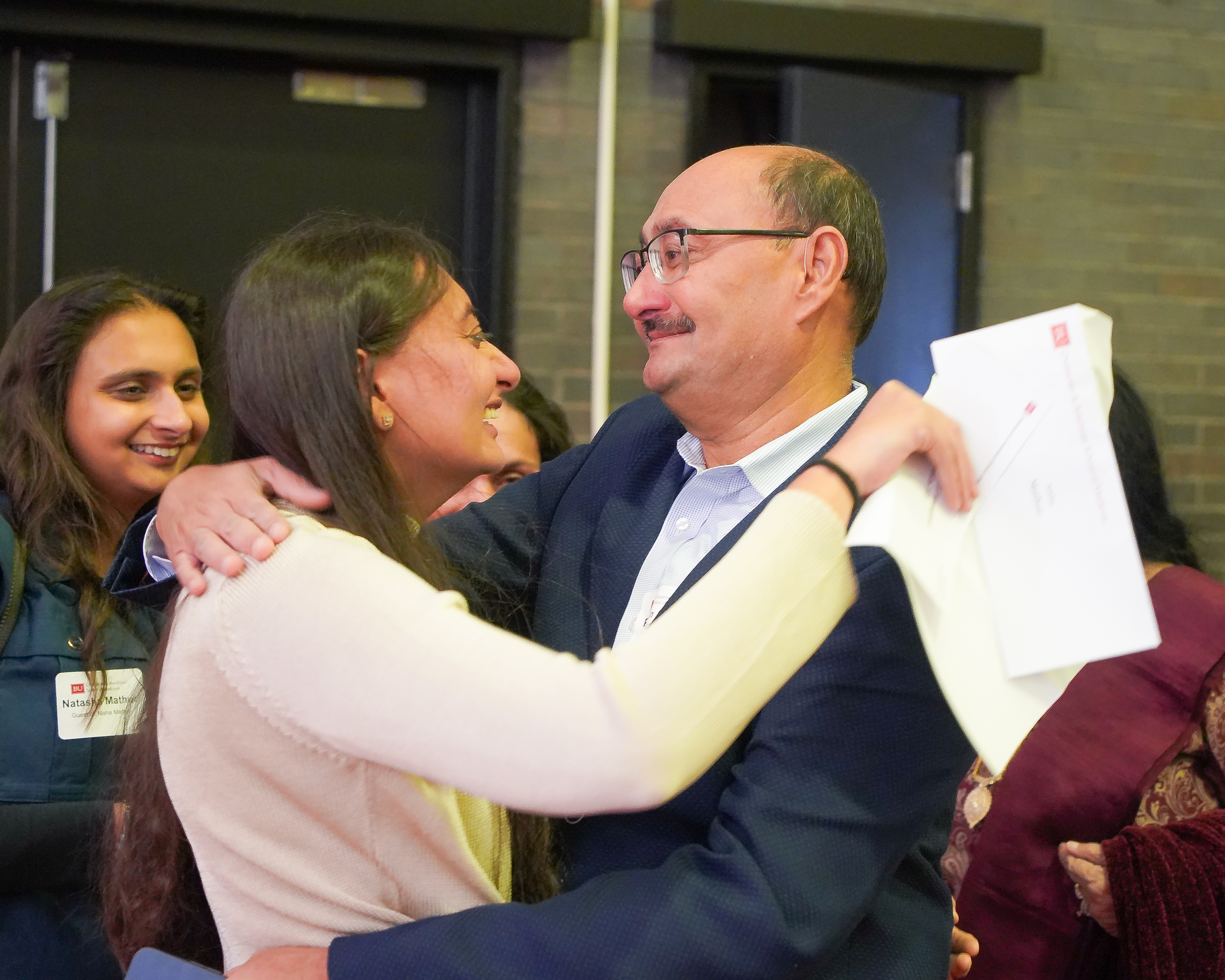 Woman hugs her father while holding white papers with her Match Day results