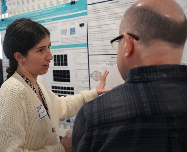 Student standing infront of her poster talking with a man about her research