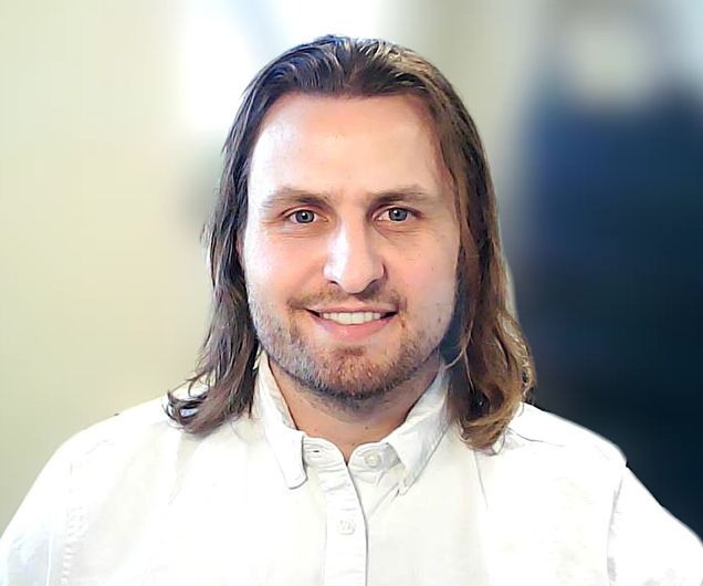 Nicholas A. Livingston white shirt, shoulder length brown hair and facial hair, smiling