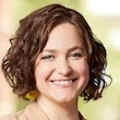 Headshot of Sarah Valentine chin length brown wavy hair, broad smile