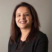 Head and shoulders shot of Shivda Pandey, shoulder length straight brown hair, black top, broad smile