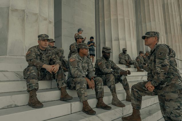 US Army member seated and standing on steps outside of the Lincoln Memorial