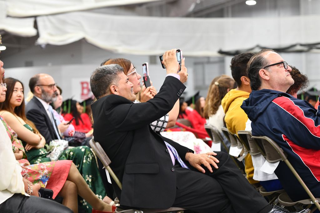 Audience seated during ceremony taking photos of graduates
