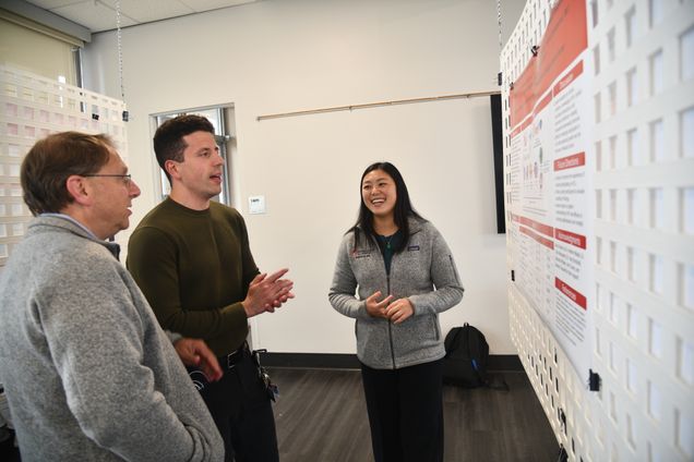 Two medical students explain their poster to faculty member
