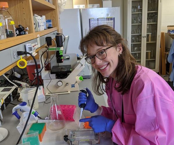 woman student in lab wearing pink labcoat