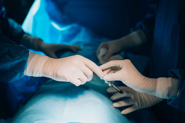 Gloved hands in operating room