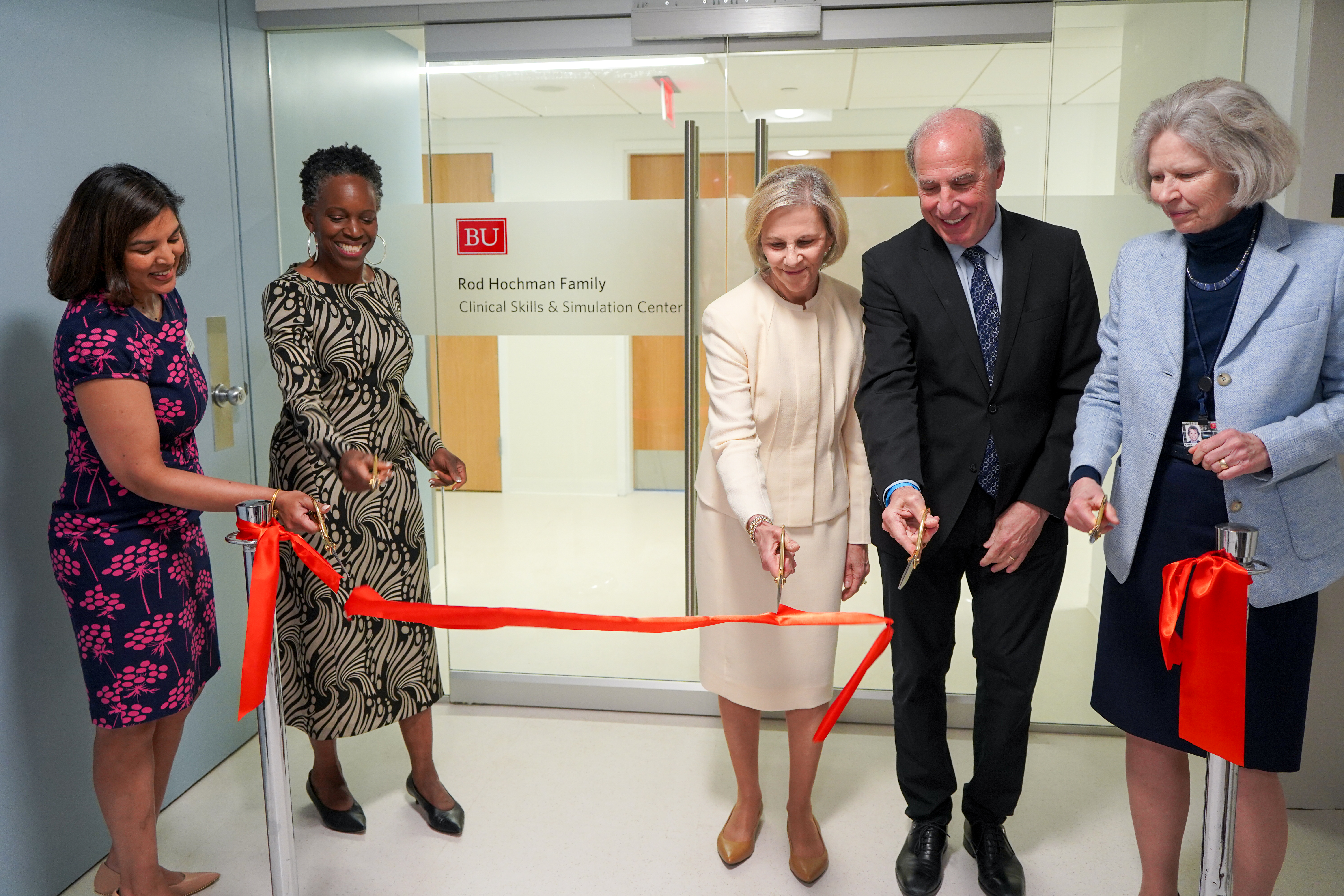 Ribbon cutting of new Center with people behind red ribbon in front of glass doors