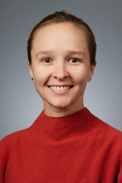 White woman with brown hair pulled back and a red shirt