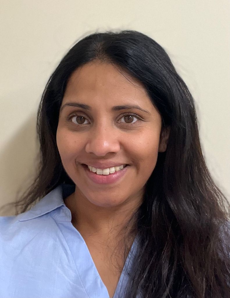 Woman with brown skin and black hair wearing a blue collared shirt