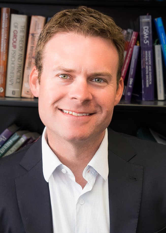 Head and shoulders image of Brian Smith infront of books on wall
