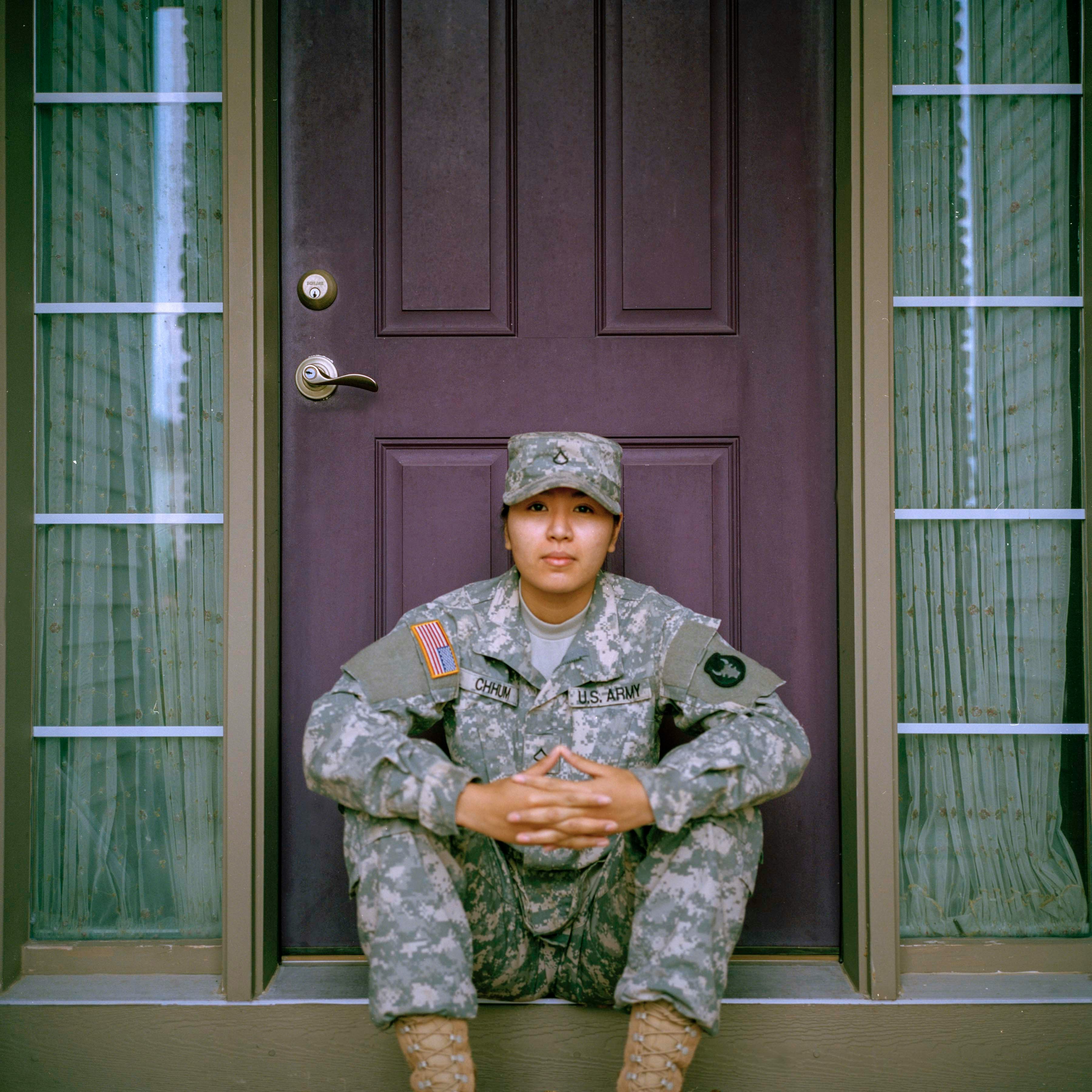 Woman US Army soldier sitting on stop in front of front door